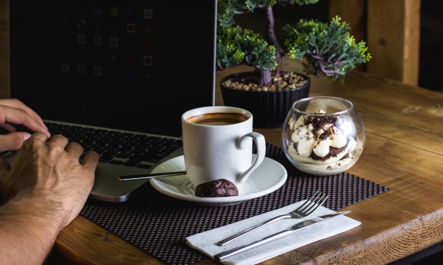 A cup of coffee and a laptop on a wooden table