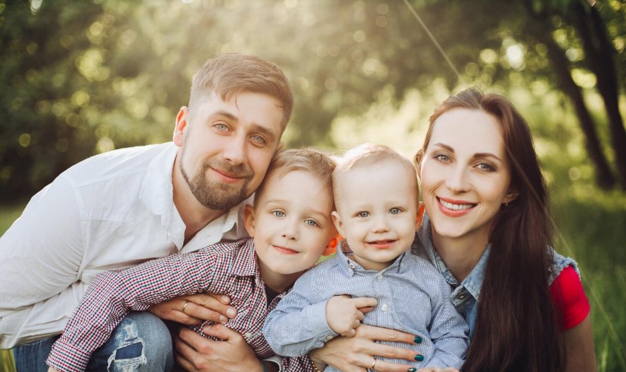 A smiling family with two young children outdoors