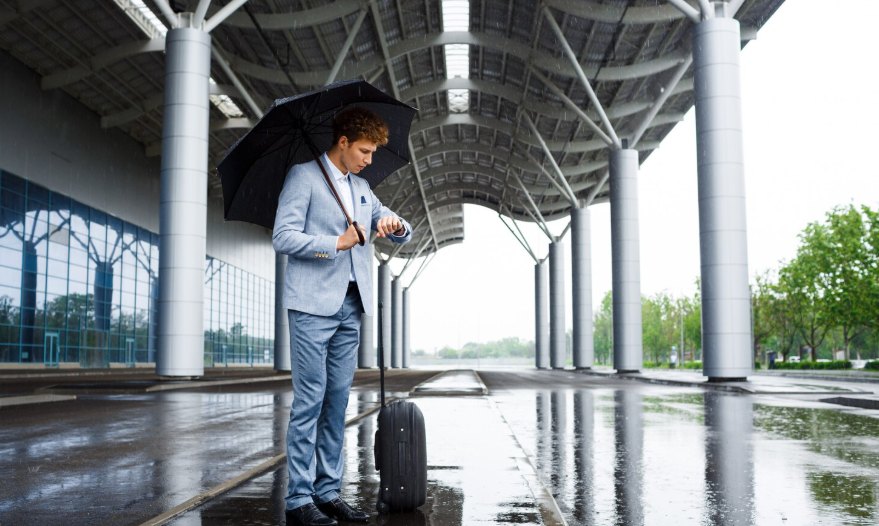 A man with an umbrella standing in a covered walkway on a rainy day